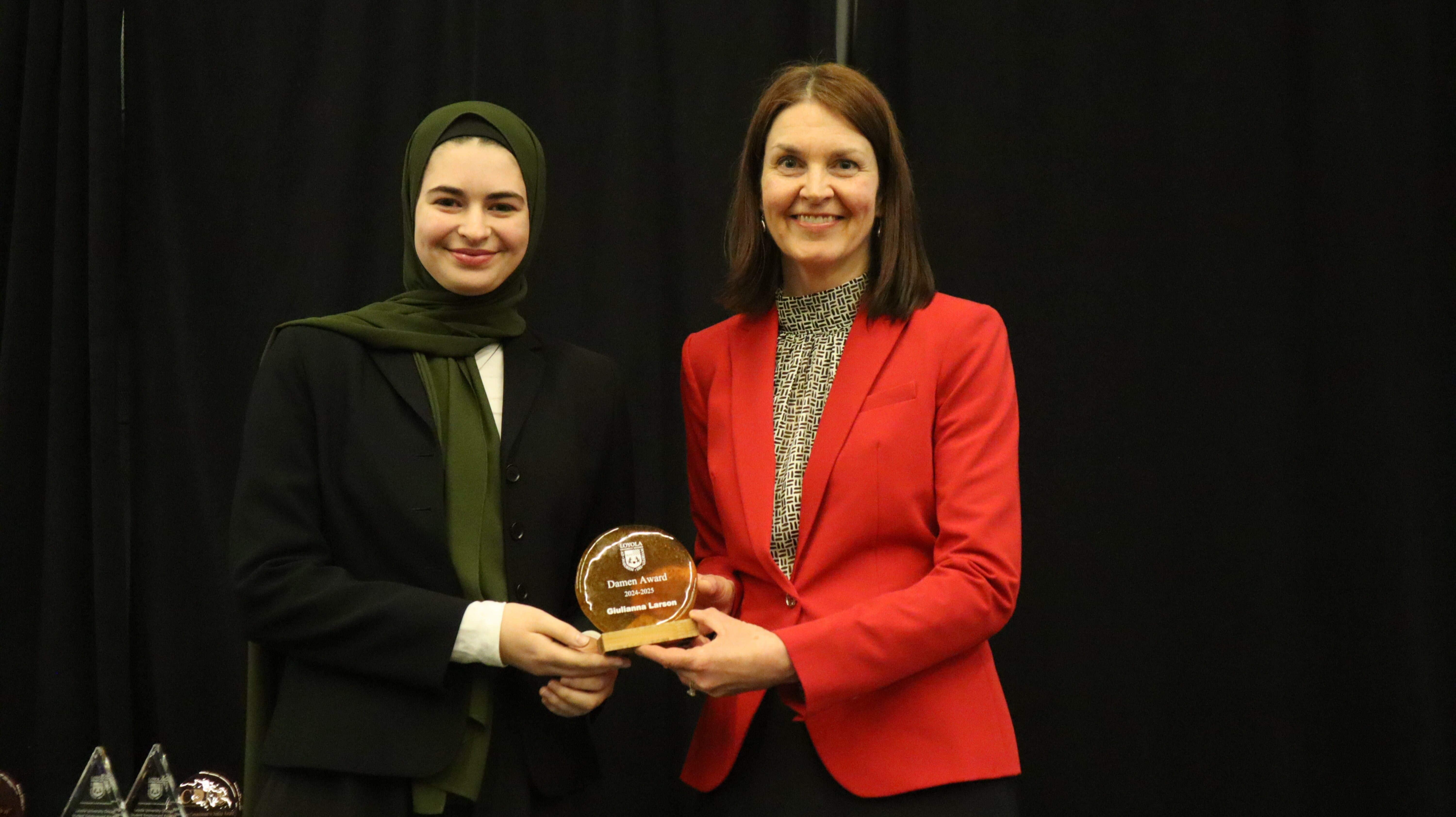 A student shakes hands with Shannon Howes and receives their award at the 2025 Excellence Awards. A student shakes hands with Shannon Howes and receives their award at the 2025 Excellence Awards.